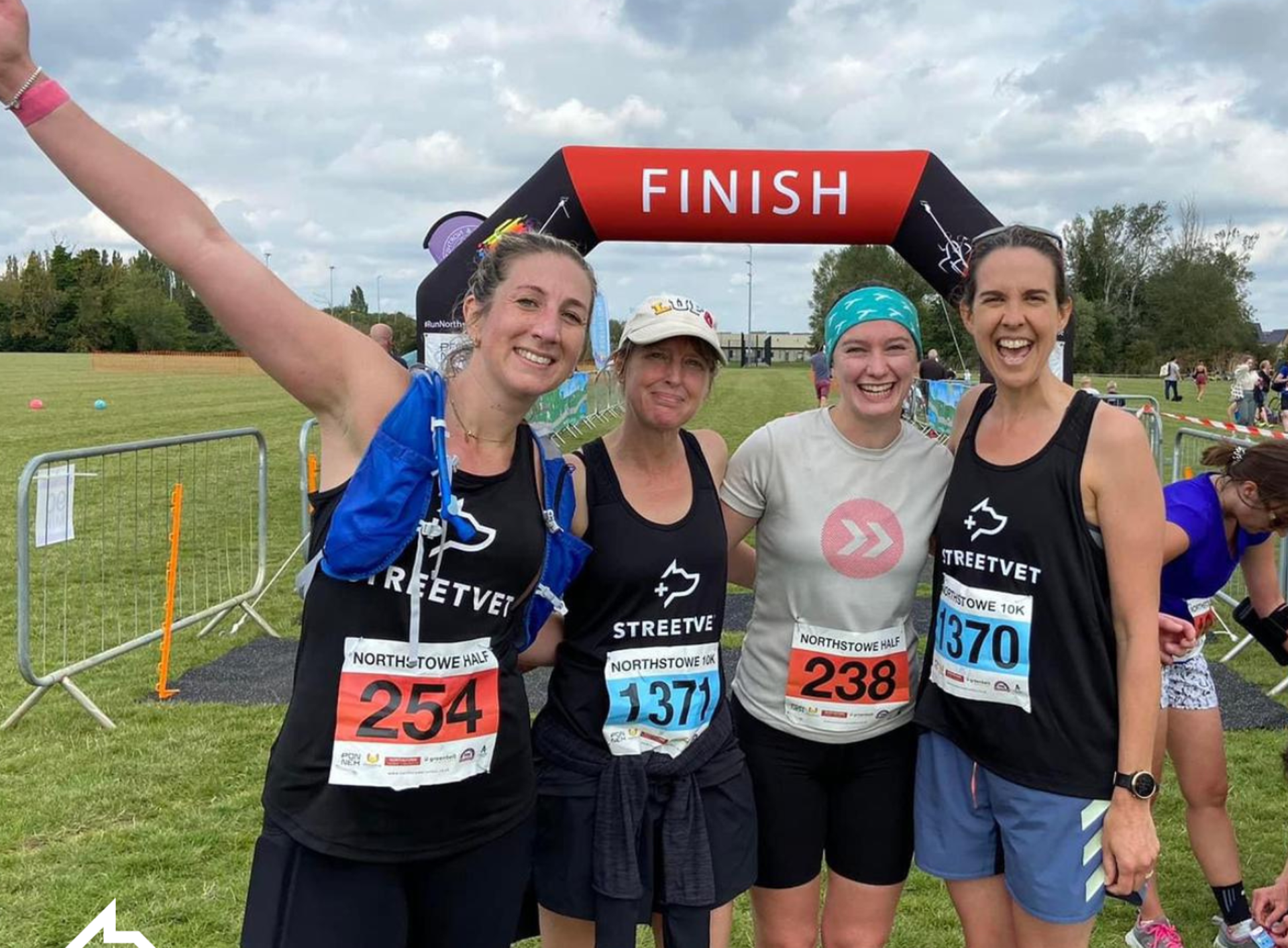 An image of four runners standing arm in arm in front of the finish line. 