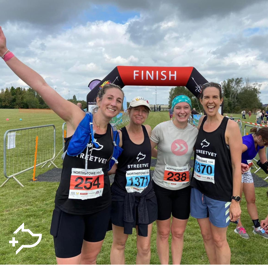 An image of four runners standing arm in arm in front of the finish line. 
